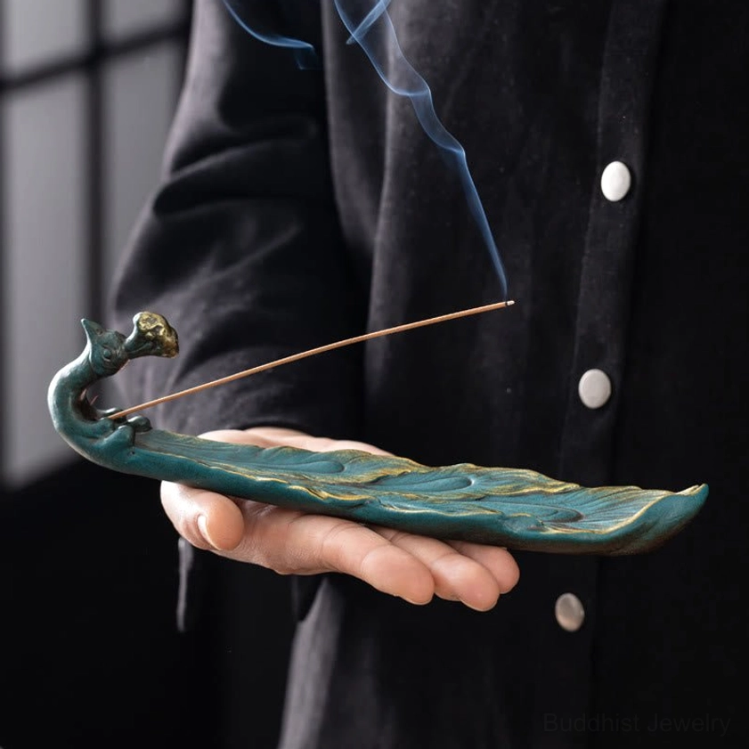 Blue-green peacock incense burner held in palm gilded head details close-up