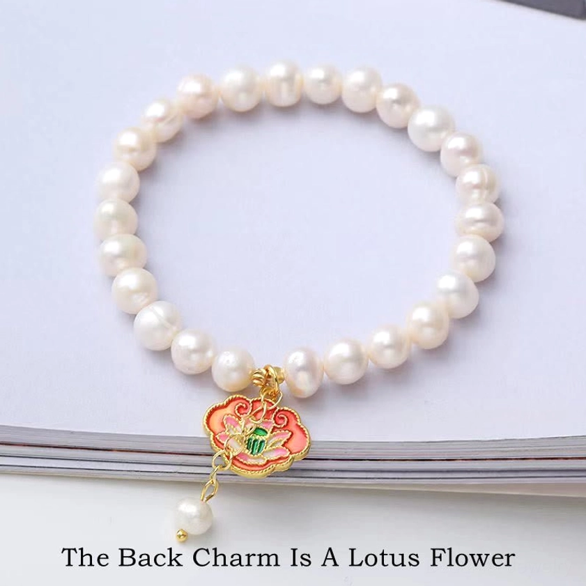 Pearl lotus Buddhist bracelet on magazine background, featuring reversible enamel lotus flower charm with pearl drop, spiritual jewelry design