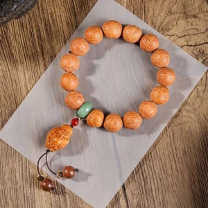 Phoenix Eye Bodhi wrist mala bracelet with turquoise and red spacer beads, displayed on wooden table