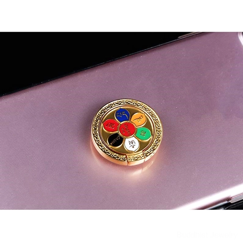 Buddhist mantra phone ring holder on smartphone displaying adhesive backing, showing peelable 3M sticker attachment method