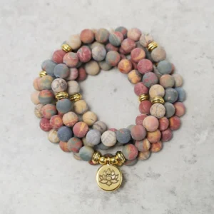 Picasso Jasper 108 mala beads bracelet with gold lotus charm on marble background, top-down flat lay view