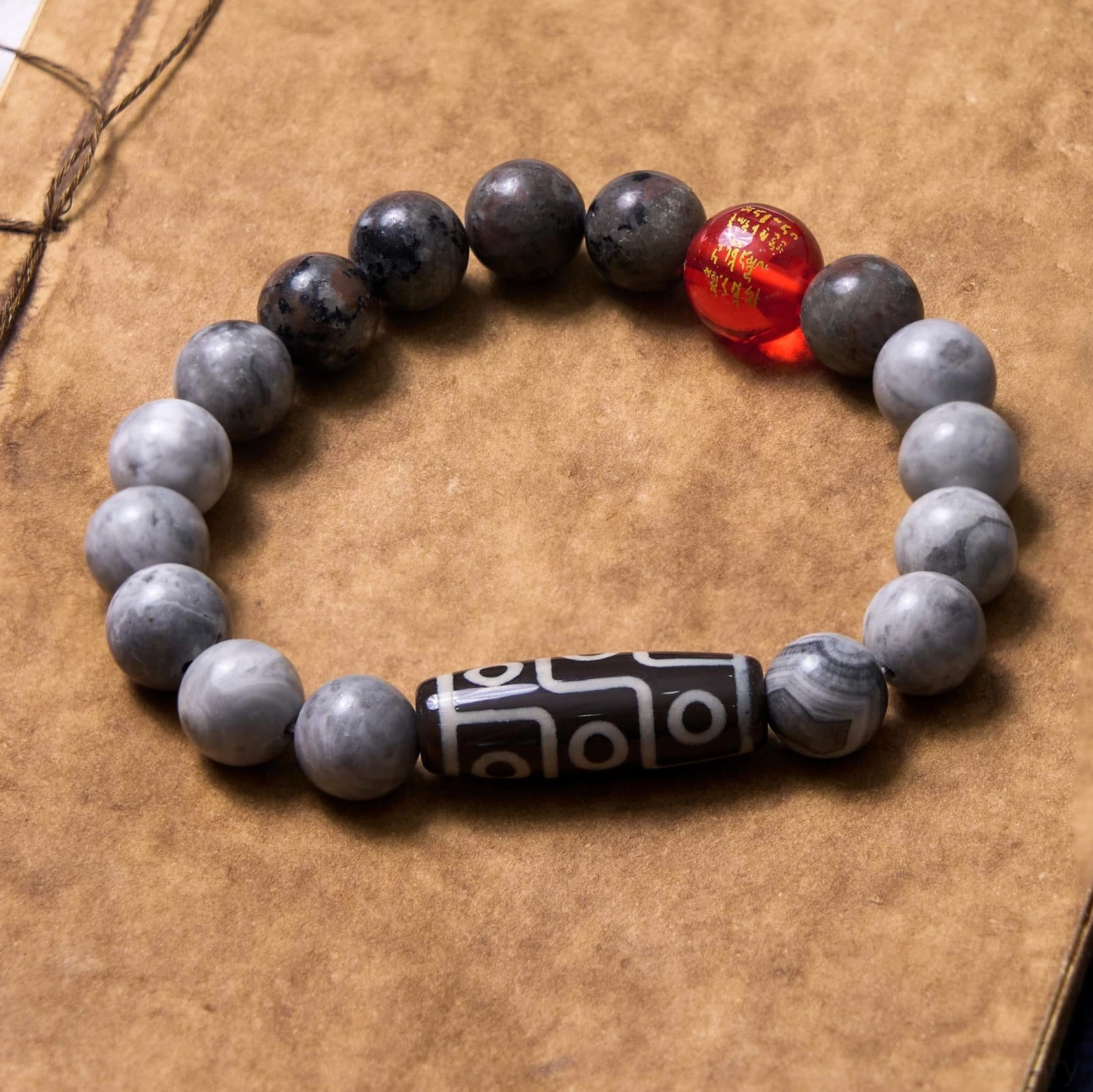 Picasso jasper dzi bead bracelet mixed gray tones with red accent bead and sacred dzi charm on vintage notebook