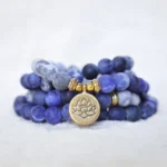 Picasso Jasper 108 mala bead bracelet with gold lotus pendant, close-up top view showing natural stone beads and metal spacers