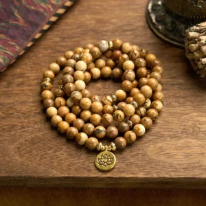 Picture jasper 108 bead mala bracelet with gold lotus charm flat lay overhead view on wooden surface
