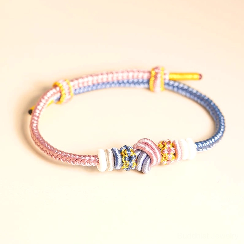 Pink and blue handwoven Buddhist bracelet with sacred knot design flat overhead shot