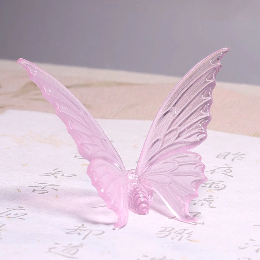 Side three-quarter view of pink translucent butterfly incense holder on calligraphy paper