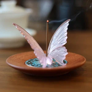 Pink Liuli glass butterfly incense burner on wooden tea table with burning incense and enamel tray