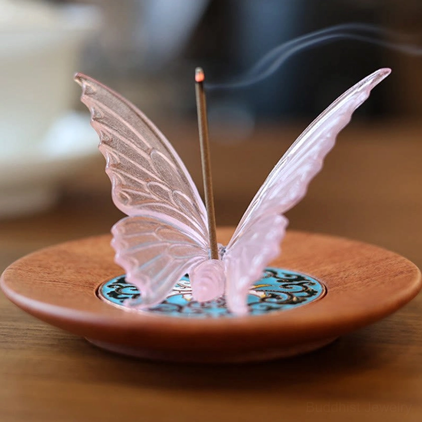 Close-up front view of pink glass butterfly incense holder with burning incense stick