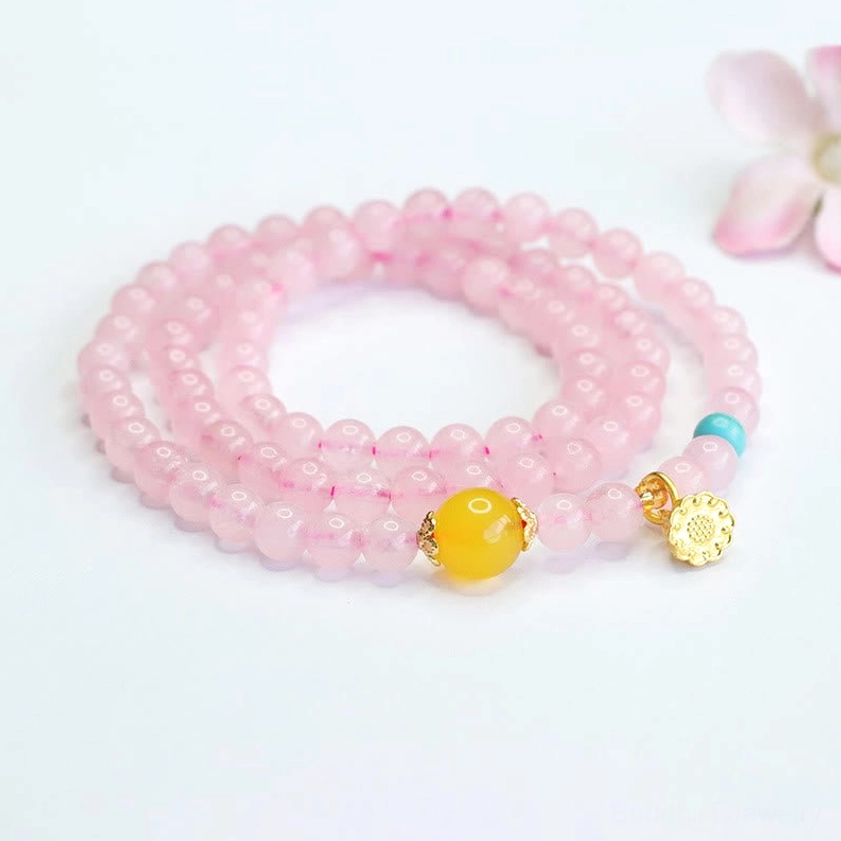 Pink crystal beaded bracelet flat lay with lotus symbol charm on light background