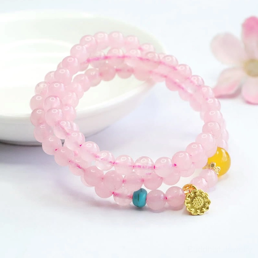 Pink crystal lotus bracelet with yellow chalcedony beads and gold charm on ceramic plate