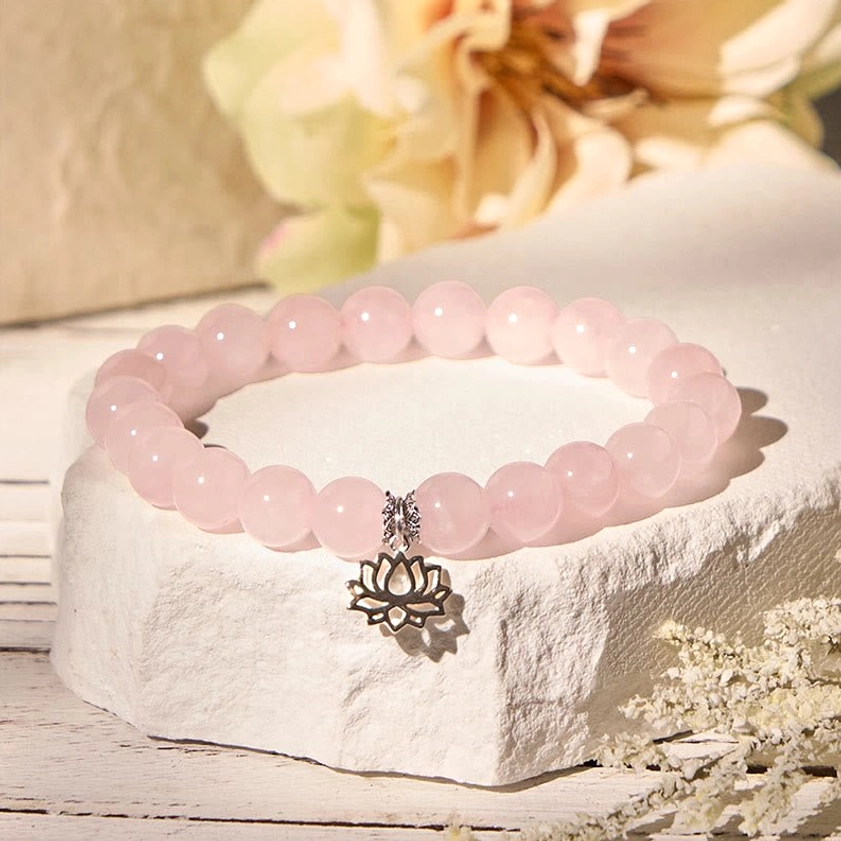 Delicate pink crystal beaded bracelet with antique silver lotus charm on stone backdrop
