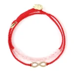 Pink crystal red string Buddhist bracelet with gold lotus charm - front overhead view showing dual-layer design, braided red cord, and transparent pink crystal beads