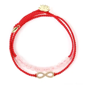 Pink crystal red string Buddhist bracelet with gold lotus charm - front overhead view showing dual-layer design, braided red cord, and transparent pink crystal beads