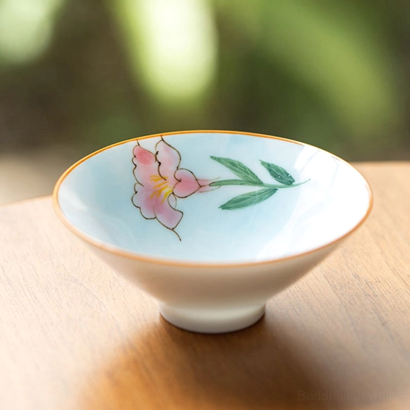 Pale blue ceramic teacup with hand-painted pink flowers and green leaves Buddhist floral design