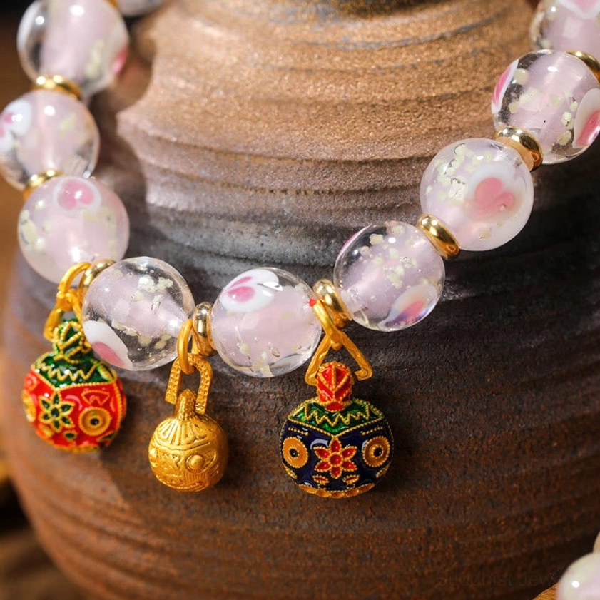 Side close-up detail of luminous pink heart pattern inside translucent liuli glass beads with enamel Buddhist charm pendants