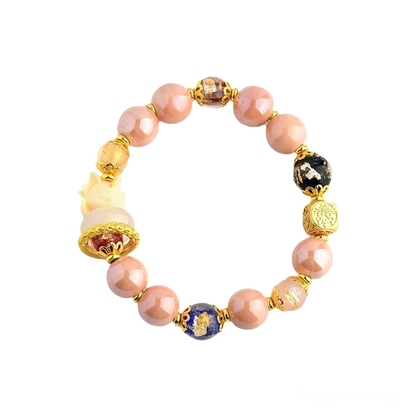 Pink glass prayer bracelet with nine-tailed fox charm, gold metal beads, blue patterned decorative bead, and black spiritual symbol bead, overhead flat lay