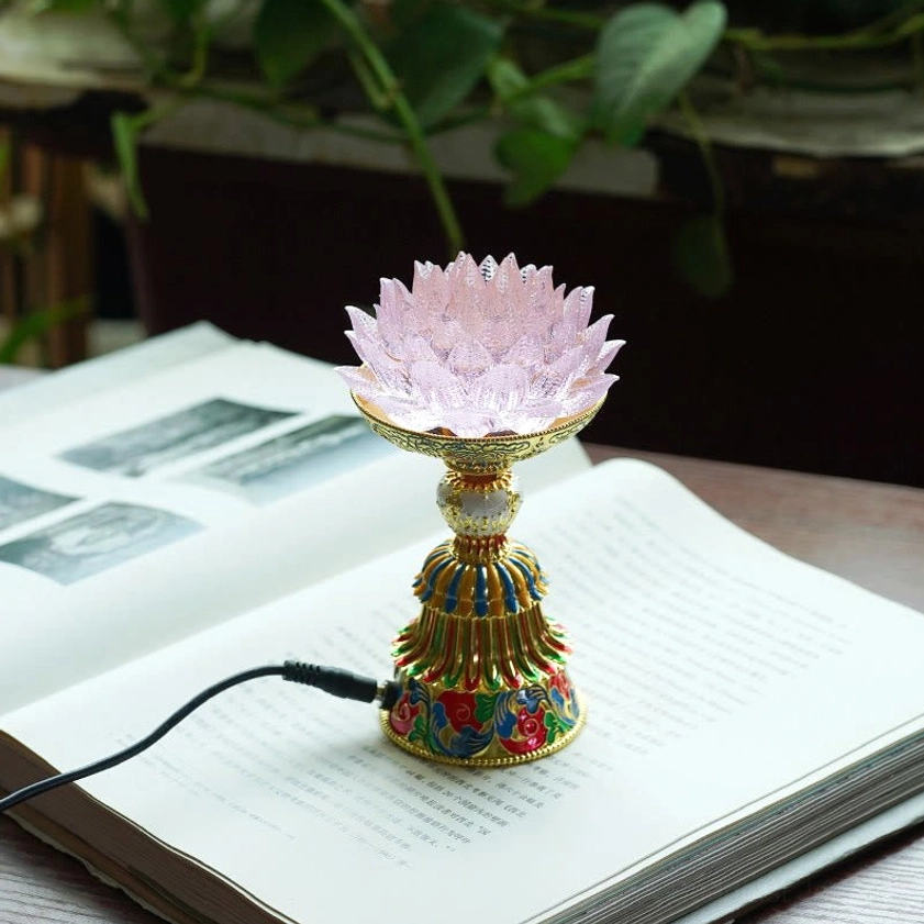 Pink liuli glass lotus lamp with pale petals and decorative enamel base on open book