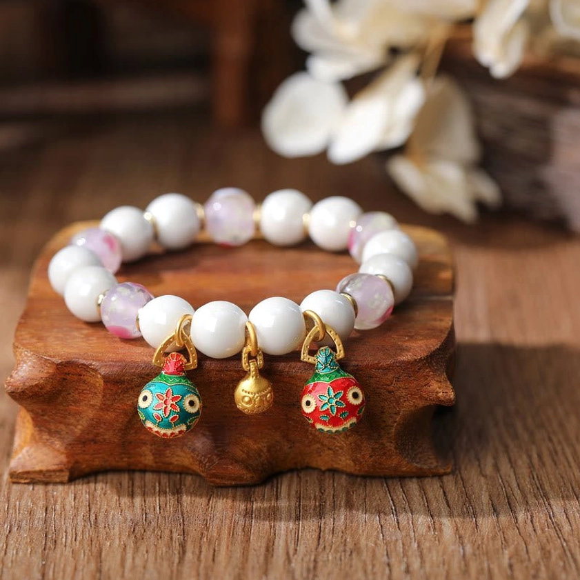 Gradient pink and white liuli glass bracelet with fish-shaped enamel pendant and gold bell charm