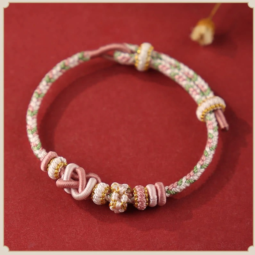 Pink peace knot Buddhist bracelet flat lay - handcrafted with gold accents for loving-kindness and spiritual compassion