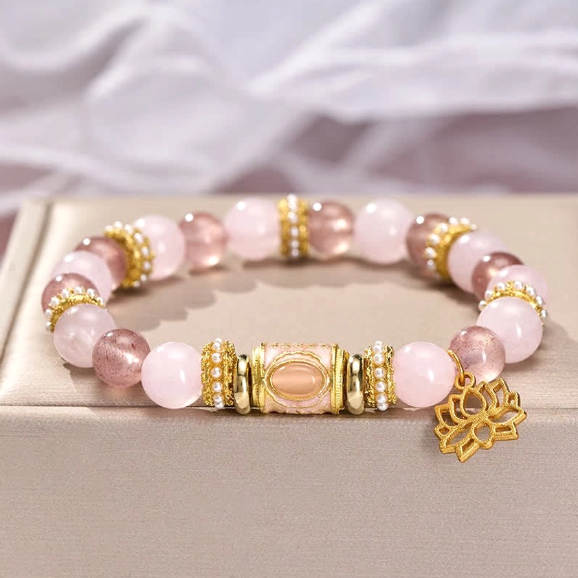 Buddhist bracelet flat lay showing strawberry quartz and rose quartz beads with gold lotus charm detail