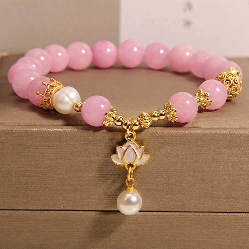 Pink Quartzite Lotus Pearl Buddhist Bracelet - Overhead oblique view displaying 8mm pink quartzite beads, freshwater pearl, and gold-toned lotus charm pendant on wooden display