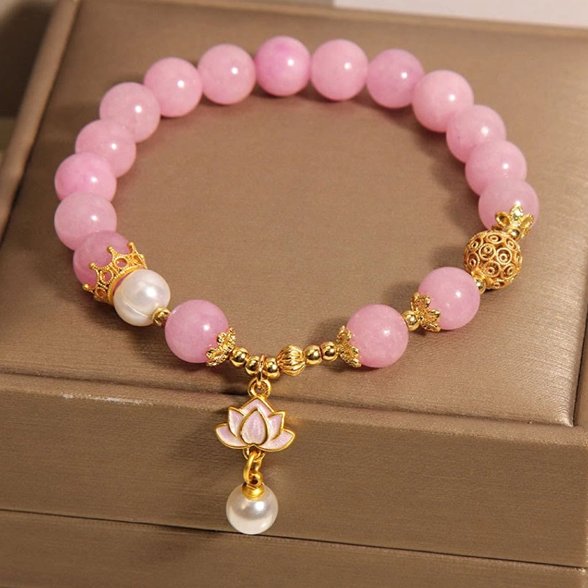 Pink Quartzite Lotus Pearl Bracelet - Front centered view highlighting gold-toned lotus drop pendant with pearl on brown jewelry tray