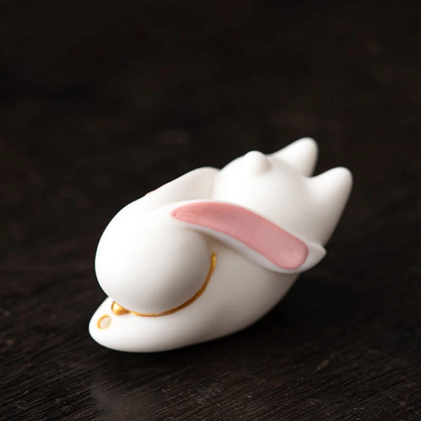 Pink ceramic rabbit incense burner with smooth glaze on blue floral bamboo mat