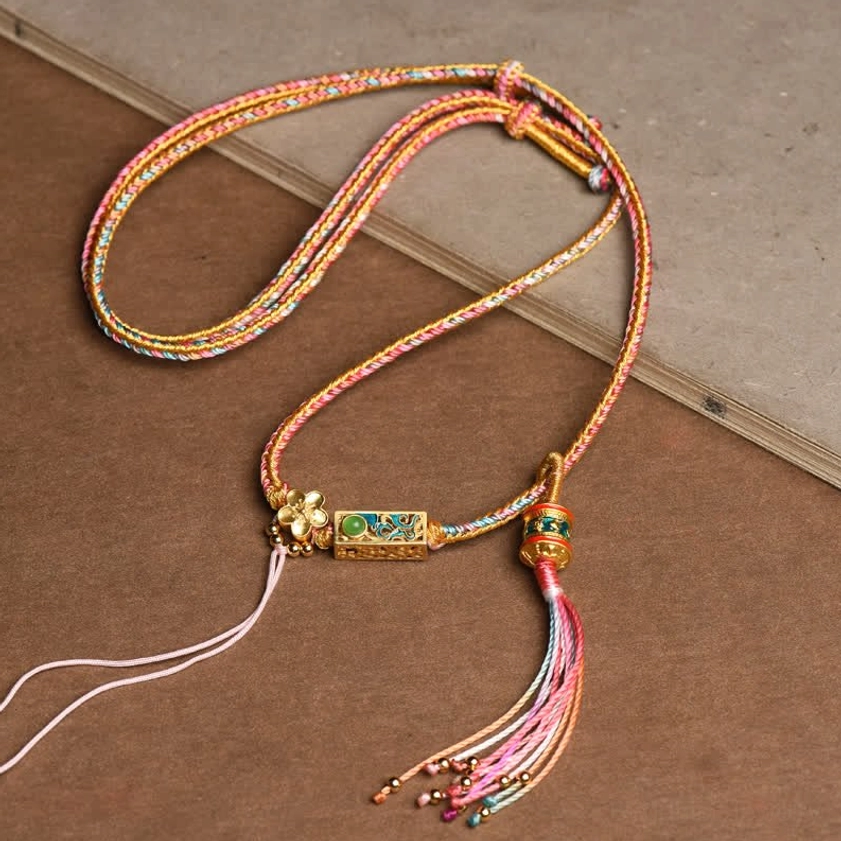 Pink and yellow braided copper string Buddhist necklace pendant with gradient tassel and gold enamel charm, handcrafted for prosperity