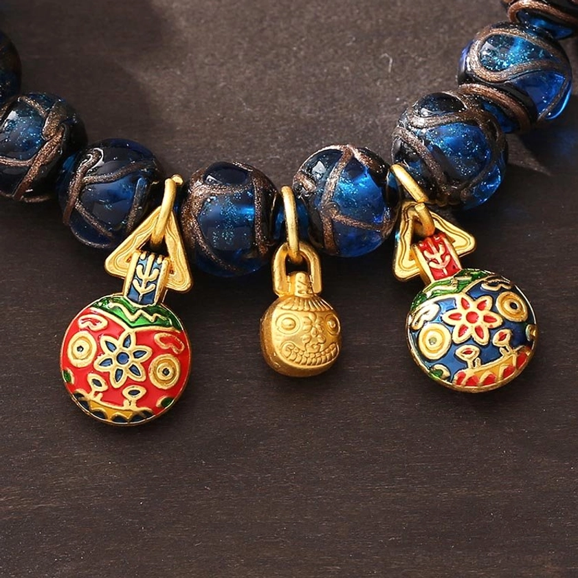 Close-up detail of blue liuli glass beads and gold-plated pixiu charm clasp on prosperity bracelet
