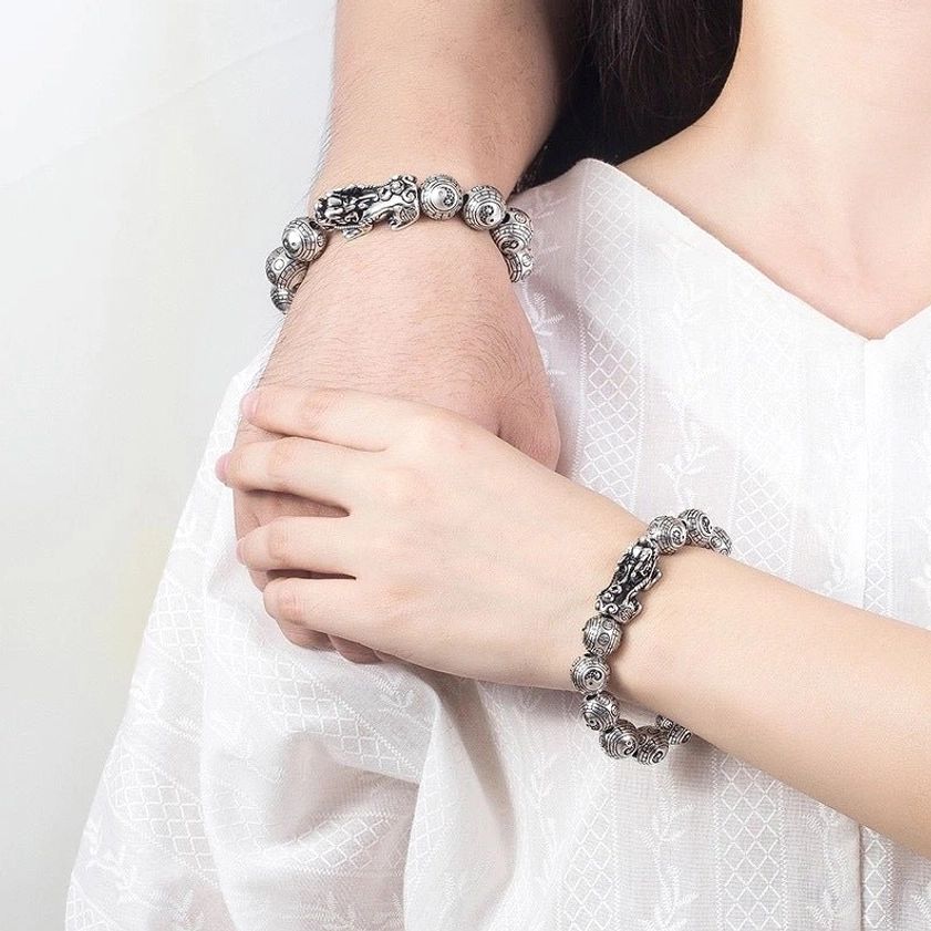 Buddhist Pixiu wealth bracelet worn on both wrists in lifestyle setting, vintage silver beaded design with protective guardian charms, prosperity jewelry