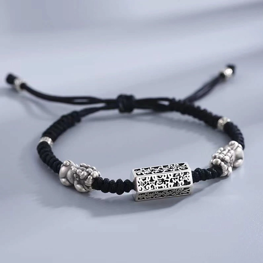 Black braided bracelet with Pixiu and scripture tube charm detail shot low angle view