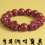 Double Pixiu cinnabar bracelet with om mani padme hum beads close-up detail on yellow background