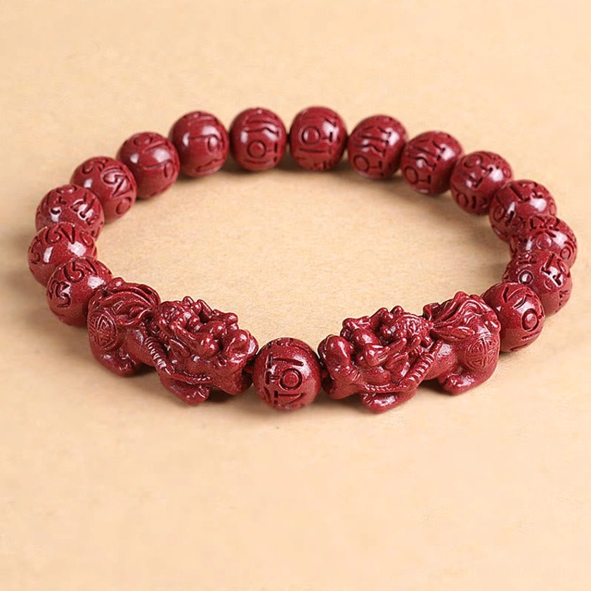 Flat lay complete cinnabar Pixiu bracelet showing pair of charms and round beads