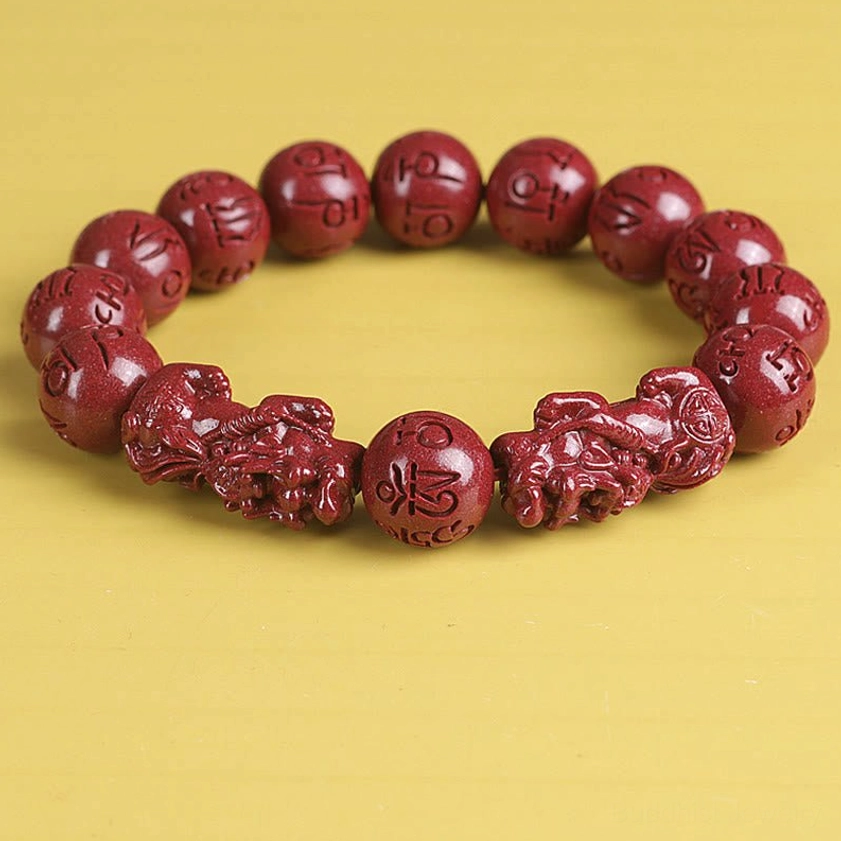 Flat lay cinnabar Pixiu bracelet displaying uniform red beads and large central charm