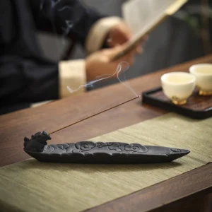 Pixiu auspicious clouds ceramic incense burner matte black with embossed design on tea table with rising smoke