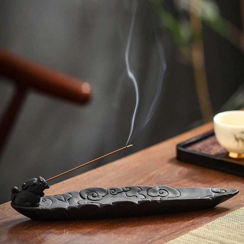 Pixiu cloud ceramic incense stick holder side view with curling smoke on traditional tea table
