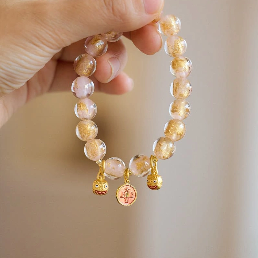 Clear gradient glass bead wealth attraction bracelet with gold pixiu beast and copper coin charms - flat lay