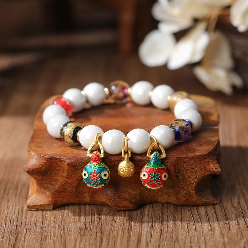 Handmade beaded lucky charm bracelet with white main beads, brown accents and gold hardware charms