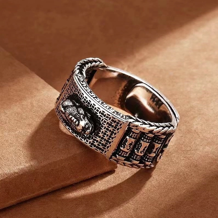 Pixiu fortune ring for men - side close-up showing braided ring edges, embossed prosperity motif, and vintage silver finish on brown paper background