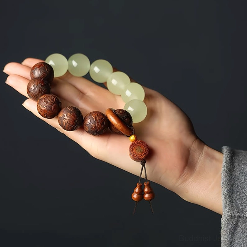 Dark carved wood and pale green jade beaded Buddhist bracelet with decorative tassel pendant, side angle