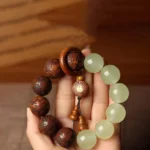 Sappan wood Pixiu Fu character Buddhist bracelet with jade beads, overhead view on wooden surface