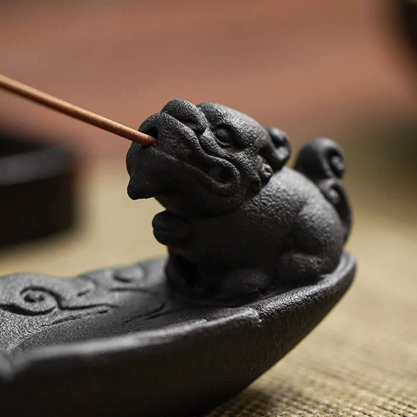 Pixiu mouth incense holder extreme close-up showing ceramic texture and incense stick insertion