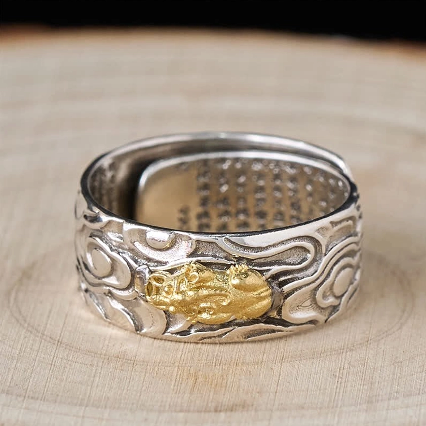 Front face view of Pixiu Heart Sutra adjustable ring with prominent gold Pixiu symbol on silver band, light wooden background