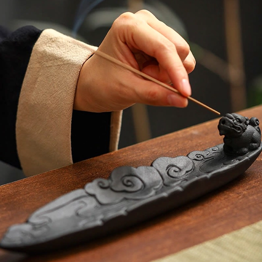 Close-up Pixiu ceramic incense holder showing embossed cloud details and incense stick placement