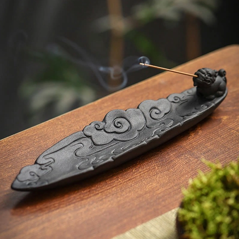 Handcrafted Pixiu ceramic incense holder three-quarter view with lit incense stick on wooden tea table