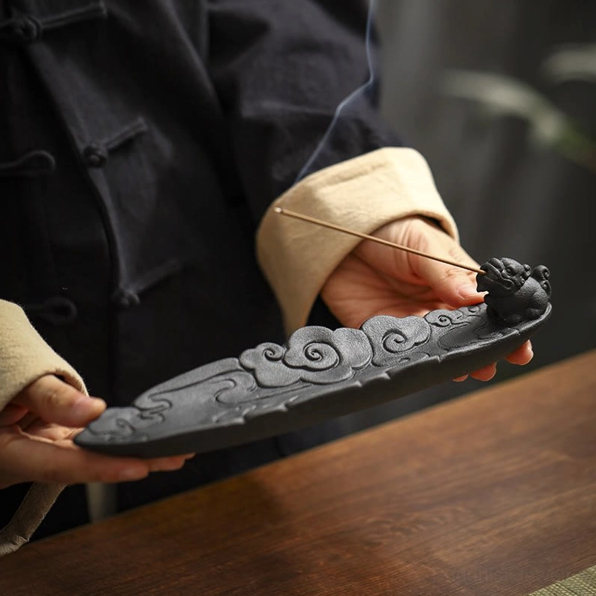 Buddhist Pixiu ceramic incense burner held in hands showing matte black texture and embossed details