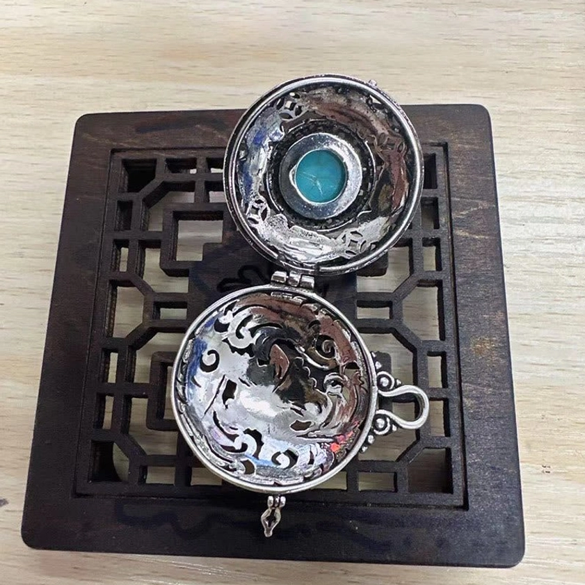 Opened pixiu locket necklace showing inner carved silver patterns