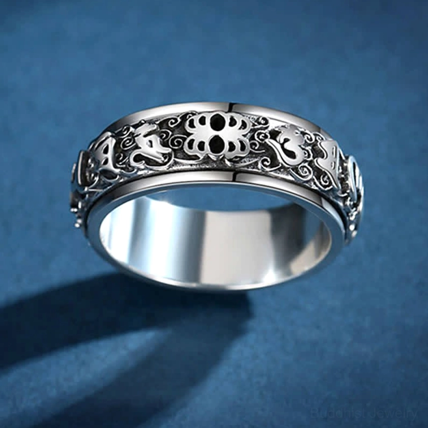 Rotatable Buddhist mantra ring with Pixiu guardian and Om Mani Padme Hum sutra, top-down view displaying embossed decorative patterns and polished inner band