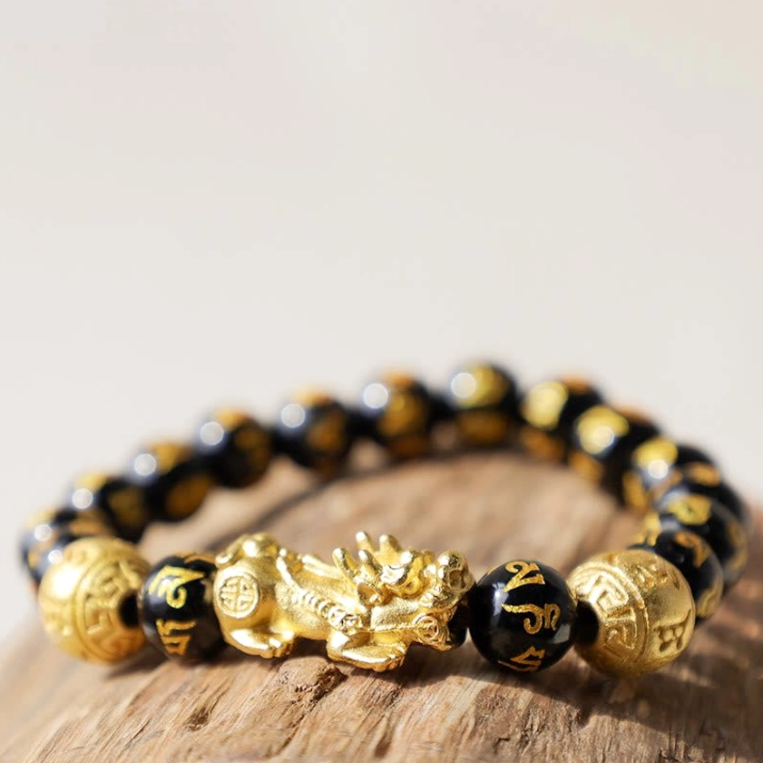 Buddhist prosperity bracelet featuring elastic beaded design with black obsidian, gold Pixiu charm, and sacred mantra engravings