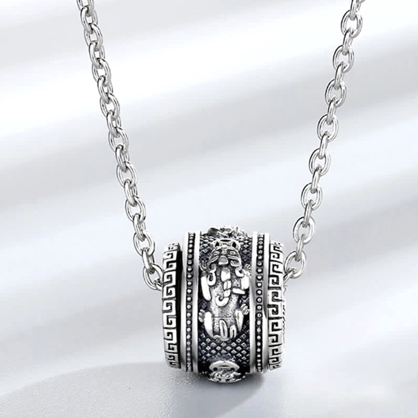 Close-up front view of Pixiu rotating pendant necklace with twisted metal chain and embossed vintage silver Buddhist details